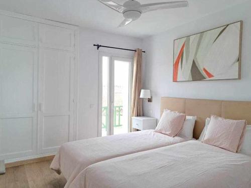 een witte slaapkamer met een bed en een plafondventilator bij Costa Guacimeta Apartment in Los Pocillos