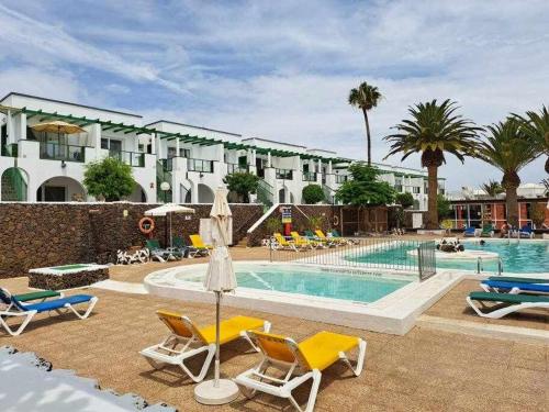 een zwembad met stoelen en een hotel bij Costa Guacimeta Apartment in Los Pocillos