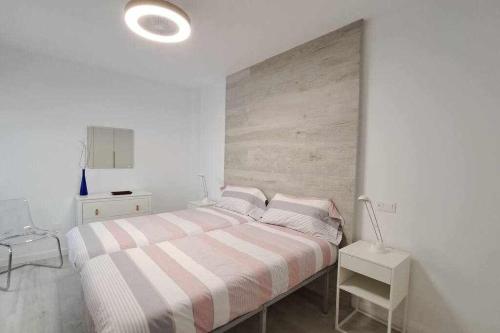 a white bedroom with a bed with a striped blanket at ARQ Home Arrecife in Arrecife