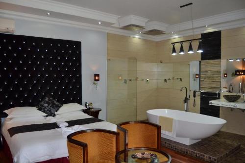 Staybridge Riverside Hotel & Spa في Broadhurst: غرفة نوم مع حوض وسرير وحمام