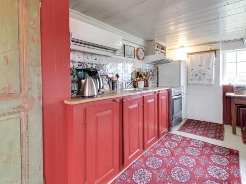 a kitchen with red cabinets and a red wall at Holiday Home Saarah - 25km from the sea in Western Jutland by Interhome in Bredebro