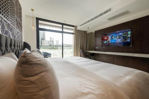 a bedroom with a large bed with a tv on the wall at Tajreed Suites in Riyadh