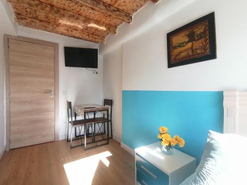 a room with a blue wall and a table with flowers on it at Habitaciones Casa Santander Playa Valdenoja in Santander