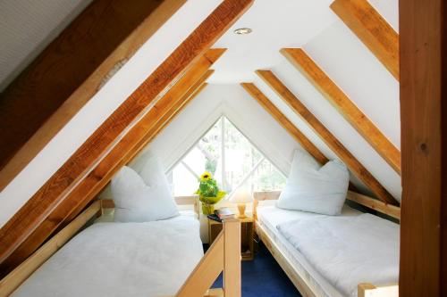 two beds in a attic room with a window at Ferienhaus Wolters in Ostseebad Karlshagen