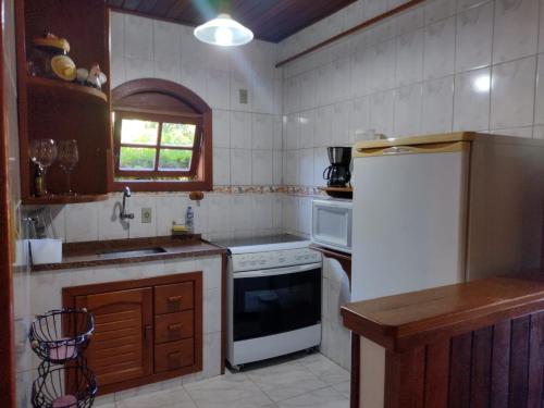 a kitchen with a white refrigerator and a sink at Casa Temporada em Lumiar in Lumiar