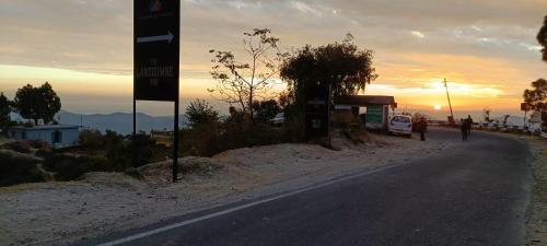 a person walking down a road with the sunset in the background at Mountain green valley homestay in Lansdowne