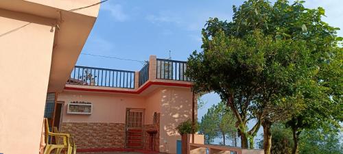 a house with a balcony and a dog sitting on the balcony at Mountain green valley homestay in Lansdowne
