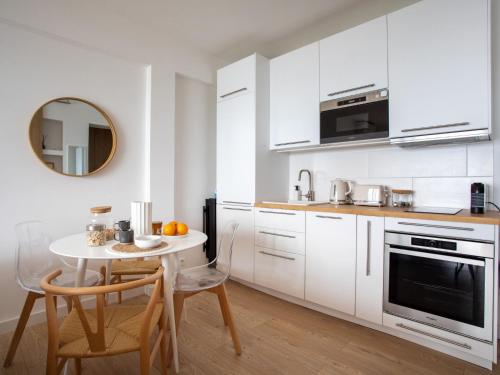une cuisine blanche avec une petite table et un miroir dans l'établissement Apartment L'Angelina-2 by Interhome, à Cagnes-sur-Mer