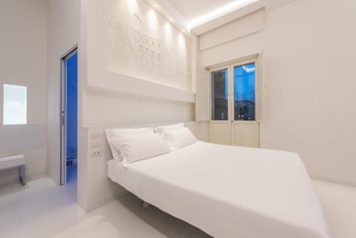 a white bedroom with a white bed and a window at Vittorio Veneto Matera Luxury Rooms in Matera