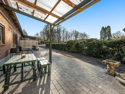 a patio with a table and benches under a pergola at Apartment Evina - 17km to the inlet in Western Jutland by Interhome in Skjern