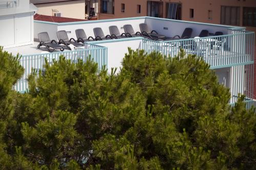 a building with chairs and trees in the foreground at Hotel Raffaello in Caorle