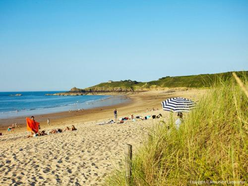 a beach with people laying on the sand and an umbrella at Apartment Vue Eméraude by Interhome in Cancale
