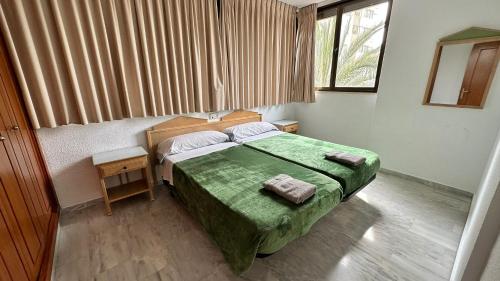 a bedroom with a green bed and a window at Esperanto 17. in Benidorm