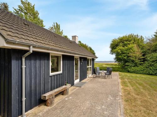 a black house with a bench and a table at Holiday Home Ødger - 150m to the inlet by Interhome in Åbybro