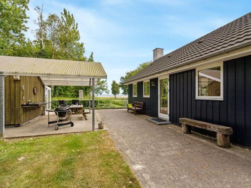 a black house with a patio and a bench at Holiday Home Ødger - 150m to the inlet by Interhome in Åbybro