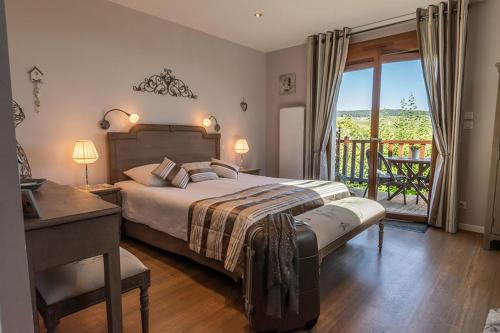 ein Schlafzimmer mit Bett und Schreibtisch und ein Balkon in der Unterkunft Clos du Mont Rouge in Bouzy