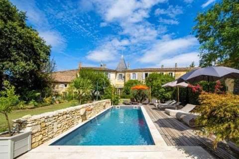 a swimming pool in a yard with a stone wall at Le Clos Réaud in Blaye