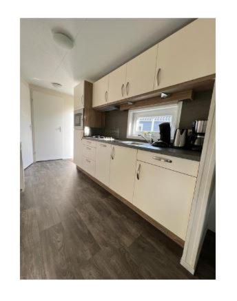 a kitchen with white cabinets and a counter top at Chalet Seebrise in Lathum