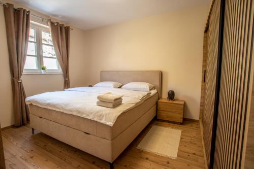 a bedroom with a bed with white sheets and a window at Landena Apartments Lendava in Lendava