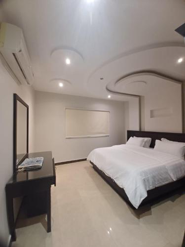 um quarto com uma grande cama branca e uma secretária em شقق طلائع الدانه للوحدات السكنية المفروشة em Riyadh