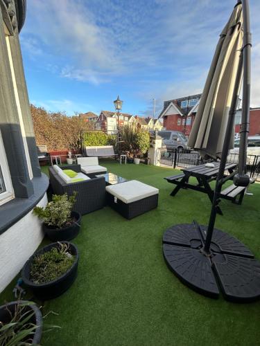 een patio met een parasol en een tafel en stoelen bij North Crest in Blackpool