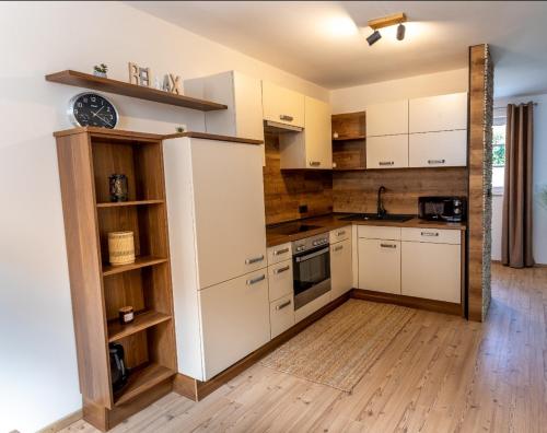 een keuken met witte kasten en een houten vloer bij Landena Apartments Lendava in Lendava