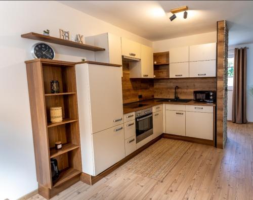 a kitchen with white cabinets and a wooden floor at Landena Apartments Lendava in Lendava