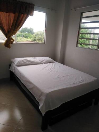ein weißes Bett in einem Schlafzimmer mit einem Fenster in der Unterkunft Hermoso apartamento in La Dorada