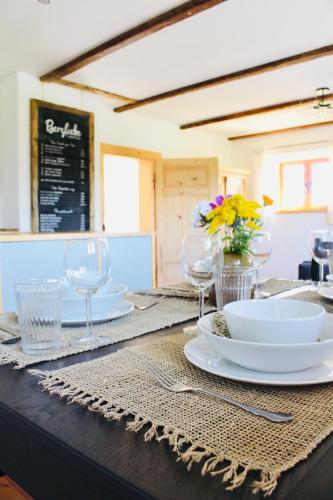 ein Tisch mit Tellern, Gläsern und Blumen darauf in der Unterkunft Ferienwohnung Bergliebe Höhenmoos in Rohrdorf