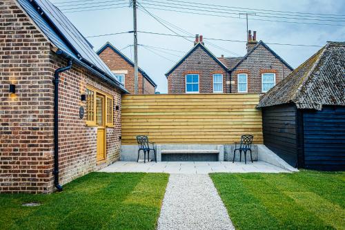 a patio with two chairs and a wooden wall at The Stable in Canterbury