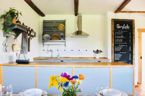 eine Küche mit einer Theke und Blumen auf einem Tisch in der Unterkunft Ferienwohnung Bergliebe Höhenmoos in Rohrdorf