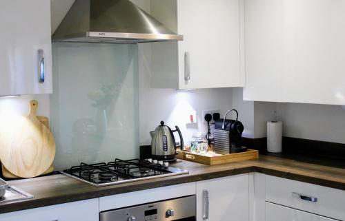 een keuken met witte kasten en een fornuis met oven bij Cicero Fairfields by Pay As U Stay in Milton Keynes