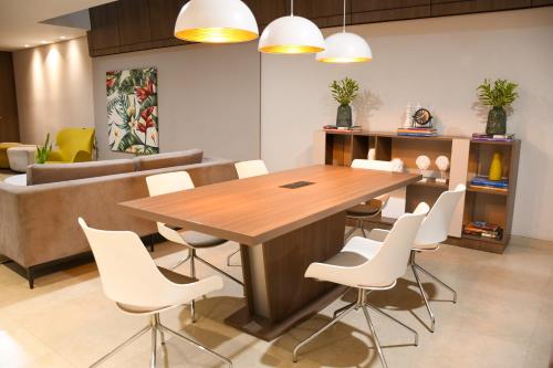 a dining room with a wooden table and white chairs at Hotel Arizona Suites Cúcuta in Cúcuta