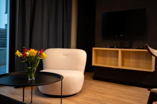 a living room with a chair and a table with flowers at Apartament No1 Wyszyńskiego in Wrocław