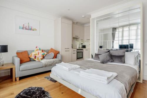 a white bedroom with a large bed and a couch at The Hyde Park Corner in London