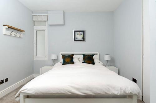 um quarto branco com uma grande cama branca e 2 almofadas em Charming Ground Floor 1 Bedroom Flat in Twickenham em Twickenham