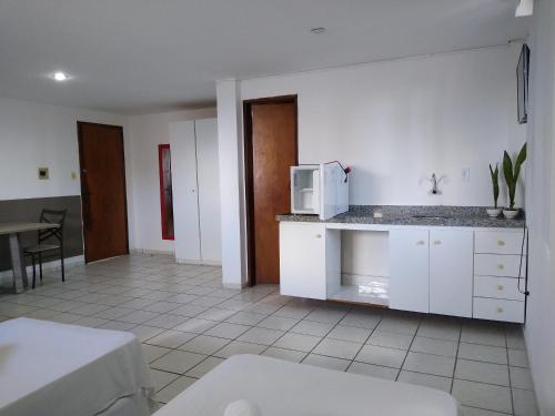 a kitchen with white cabinets and a microwave on a counter at One Hotel in João Pessoa