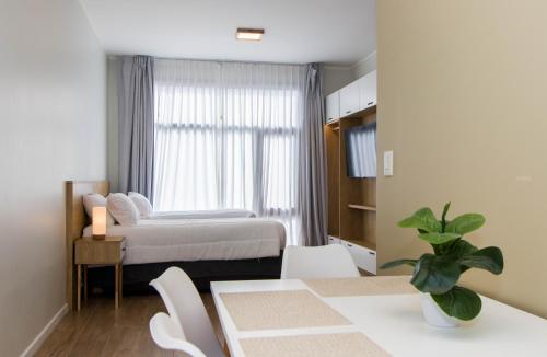 1 dormitorio con 1 cama, mesa y sillas en Criollos Apartamentos en Ushuaia