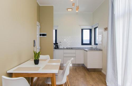 a kitchen with a white table and white chairs at Criollos Apartamentos in Ushuaia