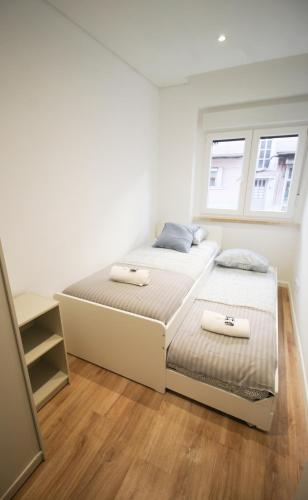 a white bedroom with two beds and two windows at Oriente DNA Studios X in Lisbon