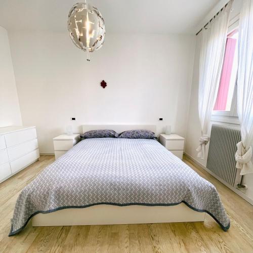 ein weißes Schlafzimmer mit einem Bett und einem Kronleuchter in der Unterkunft Incantevole appartamento sul fiume 