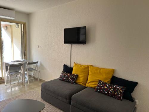 a living room with a couch and a television on the wall at Studio en rez de jardin plage de Portissol in Sanary-sur-Mer