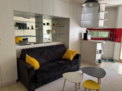 - un salon avec un canapé noir et 2 tables dans l'établissement Studio en rez de jardin plage de Portissol, à Sanary-sur-Mer