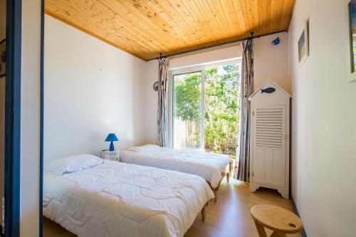 deux lits dans une chambre avec une fenêtre dans l'établissement La Villa Bleue, à Lège-Cap-Ferret