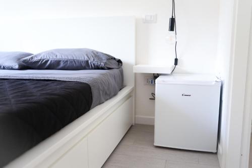 um frigorífico branco ao lado de uma cama num quarto em [Parco M. Claro] Matrimoniale con Bagno Privato. em Cagliari