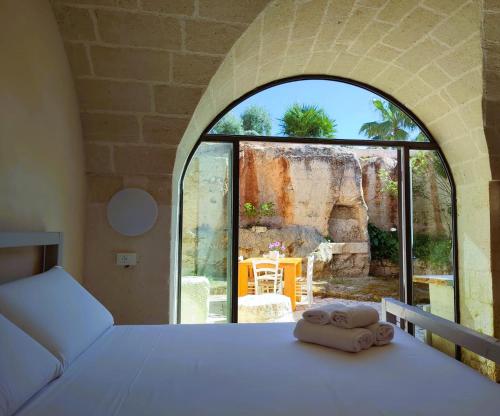 a bedroom with a bed and a large window at Masseria Piccole Taverne in Ostuni