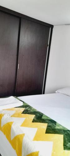 a bed with a comforter on top of it at Greenhouse- Apartamentos in Bucaramanga