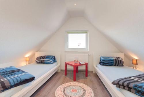 dwa łóżka w pokoju z czerwonym stołem w obiekcie Ferienhaus Wellenreiter w mieście Zierow