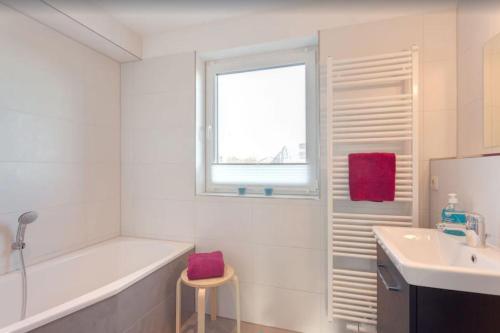 biała łazienka z wanną i umywalką w obiekcie Ferienhaus Wellenreiter w mieście Zierow