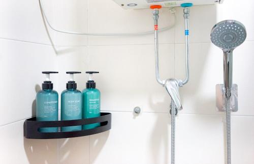 a bathroom with three bottles of shampoo and a shower at CoLiving Space - Hennessy Road 113 Wan Chai MTR in Hong Kong